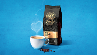 Kop koffie met Perla Superior Colombia koffiebonen en een zak Perla koffie op een blauwe achtergrond, met een hartvormige stoom.