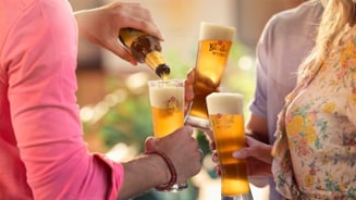 Mensen proosten met Grolsch Witbier glazen.