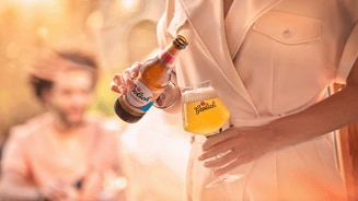Persoon in wit pak schenkt Grolsch bier in glas