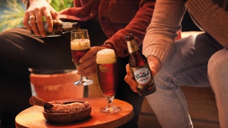Grolsch bierflesjes en glazen met bier op een tafel, met twee mensen die samen genieten van het drankje