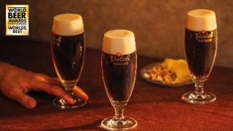 Drie glazen Grolsch Bokbier op tafel met borrelhapjes en World Beer Awards sticker in beeld