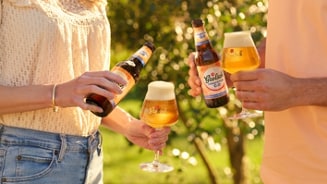 Twee mensen genieten van Grolsch 0.0% bier in een zonnige tuin.