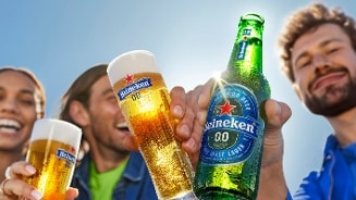Mensen vieren met Heineken 0.0 bier, fles en glazen zichtbaar in een zomerse setting.