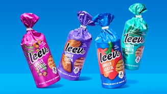 Vier verpakkingen Leev Lovely Lentil koekjes in verschillende smaken, staand tegen een blauwe achtergrond