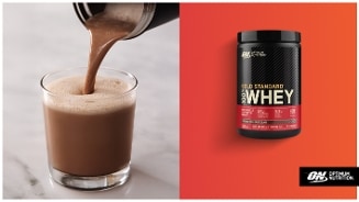 Optimum Nutrition Gold Standard Whey proteïnepoeder chocoladesmaak wordt in een glas geschonken, met verpakking op een oranje achtergrond