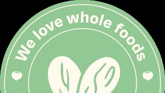 Rond logo met tekst "We love whole foods" en "The future is whole foods" met een afbeelding van twee bladeren in het midden.