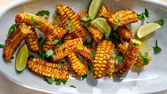 Geroosterde maïskolf met limoen en kruiden op een schaal