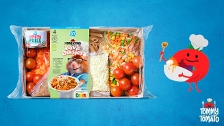 Maaltijdpakket van Albert Heijn met Tommy Tomato Lava Buisjes, inclusief tomatenpuree, cherrytomaten, gesneden groenten, kaas, volkoren penne en sausmix. Rechts een illustratie van een lachende tomaat met koksmuts en de tekst "Tommy Tomato" op blauwe achtergrond.