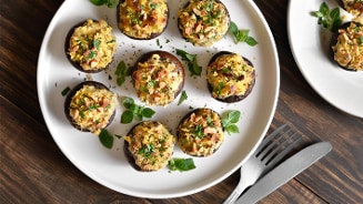 Gevulde champignons met kruiden en noten geserveerd op een witte schaal