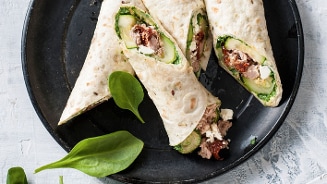 Wraps met tonijn, spinazie, komkommer, feta en zongedroogde tomaat op een zwart bord