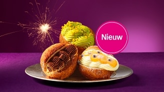 Nieuwe gebakjes met verschillende toppings op een bord met een fonkelende sterretje op de achtergrond.