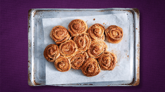 Kaneelbroodjes op een bakplaat met bakpapier