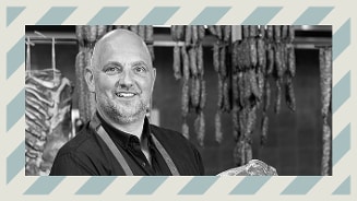 Slagerij met verschillende soorten vleeswaren in de achtergrond.