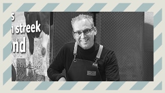 Slager in slagersuniform voor een reclamebord met koe en tekst.