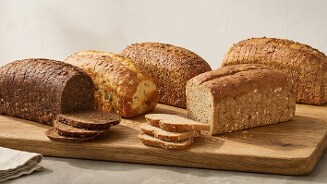 Verschillende soorten gesneden en ongesneden brood op een houten plank.