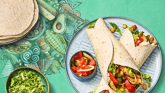 Twee burrito's gevuld met kip, paprika, maïs en sla, geserveerd met een kom tomatensalsa en geraspte sla, op een decoratieve groene achtergrond.