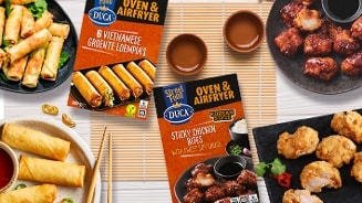 Twee DUCA Street Food Oven & Airfryer verpakkingen en diverse Aziatische gerechten, waaronder Vietnamese groenteloempia's en Korean style sticky chicken bites, gepresenteerd op borden en met dipsauzen.