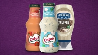 Drie flessen saus op een rij: Calvé Whisky Cocktail, Calvé Knoflook en Hellmann's Truffel mayonaise tegen een paarse achtergrond