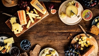 Borrelplank met blokjes en plakken Le Gruyère kaas, Tête de Moine kaas, brood, vijgen, druiven, bessen en noten op een houten tafel