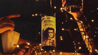 Fles 19 Crimes Red Wine tussen feestelijke lichtjes, met glazen wijn