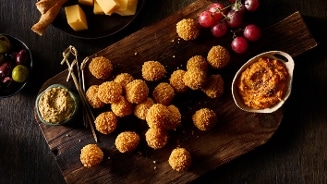 Borrelplank met bitterballen, mosterd, kaasblokjes, druiven, olijven en smeerdip op een houten plank