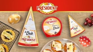 Verschillende soorten Président brie kaas op een houten tafel, omringd door druiven, decoratieve eieren en hapjes met brie.