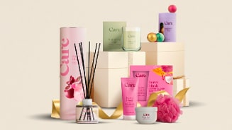 Cadeaupakket met Care beauty- en verzorgingsproducten, waaronder bodylotion, geurstokjes, bodywash, kaarsen en badaccessoires, stijlvol gepresenteerd met cadeauverpakkingen en gouden linten.