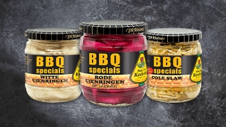 Drie potjes Kesbeke BBQ specials: witte uienringen, rode uienringen met jalapeños en cole slaw, tegen een grijze achtergrond.