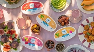 Verschillende Maza dips inclusief hoemoes en muhammara, omringd door vers fruit en olijven op een tafel.