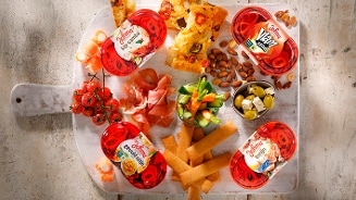 Borrelplank met verschillende Johma salades, stukjes focaccia, cherrytomaten, rauwkost, noten, olijven met feta, gedroogde ham en kaastwisters