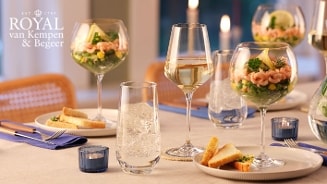 Feestelijk gedekte eettafel met glazen gevuld met een voorgerecht van garnalencocktail, witte wijn en toast, met servies van Royal van Kempen & Begeer