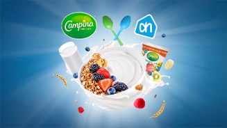 Kom yoghurt met vers fruit en granola, Campina logo, Albert Heijn logo en verpakkingen op blauwe achtergrond
