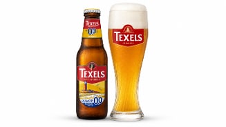 Fles Texels Skuumkoppe 0.0 speciaalbier naast een glas gevuld met het bier, met een volle schuimkraag.