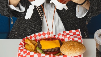 Cheeseburger met ketchup en frietjes in een rood-wit geruit mandje