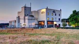 Brouwerijgebouw van Bavaria in een grasrijke omgeving tijdens zonsondergang