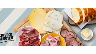 Streeckgenoten charcuterie en kaas met gesneden brood en boter op een plank.