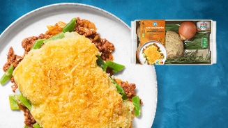 Ovenschotel van aardappelpuree, gehakt, peulvruchten en kaas, met daarnaast de Albert Heijn Seizoensfavoriet maaltijdpakket verpakking inclusief ingrediënten zoals knolselderij, ui, sperziebonen en kruiden.