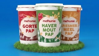 Drie bekers Melkunie pap: Gortepap, Havermoutpap en Griesmeelpap, geplaatst op een grasmat tegen een blauwe achtergrond.