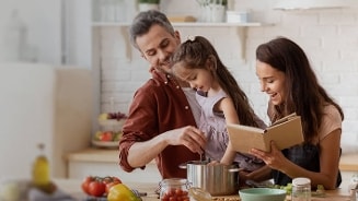 Gezin dat samen in de keuken kookt met kookboek en verse ingrediënten