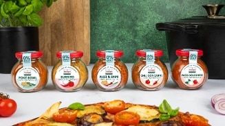 Vijf potjes van het merk Honig met kruidenmixen voor Poke Bowl, Burrito, Nasi & Bami, Chili con Carne en Pasta Bolognese, allemaal met 0% zout, geplaatst op een keukenblad met een gerecht en verse groenten op de voorgrond.