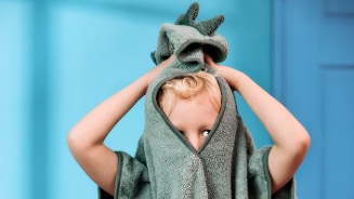 Kind zit met een groene handdoek over het hoofd.