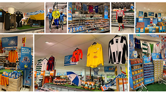 Sport gerelateerde merchandising en kledinguitstalling in een supermarkt, inclusief shirts, sjaals en fanartikelen.