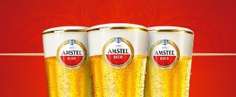 Drie glazen Amstel bier tegen een rode achtergrond.