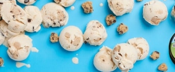 Ben & Jerry's Cookie Dough ijs op een blauwe achtergrond, met geschepte bolletjes en koekjesdeeg stukjes.