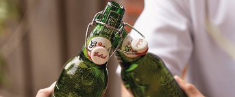 Twee mensen proosten met flesjes Grolsch bier