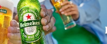Personen proosten met Heineken bierflessen en een glas Heineken bier.