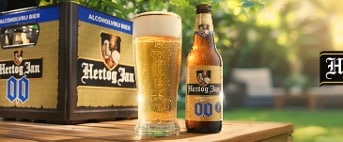 Hertog Jan 0.0% alcoholvrij bier krat, flesje en glas bier op houten tafel in zonnige tuin