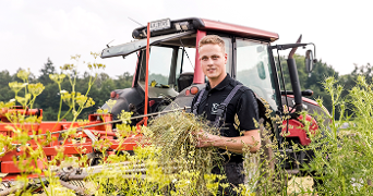 Landbouwer met een tractor en gras op het veld