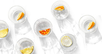 Verschillende glazen water met stukjes citrusvruchten, zoals sinaasappel, citroen en limoen, tegen een zwarte achtergrond.