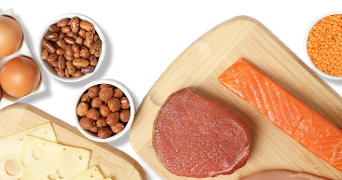 Plakjes kaas, eieren, een stuk rundvlees, een stuk zalm, bonen, hazelnoten en linzen op snijplanken en in schaaltjes.